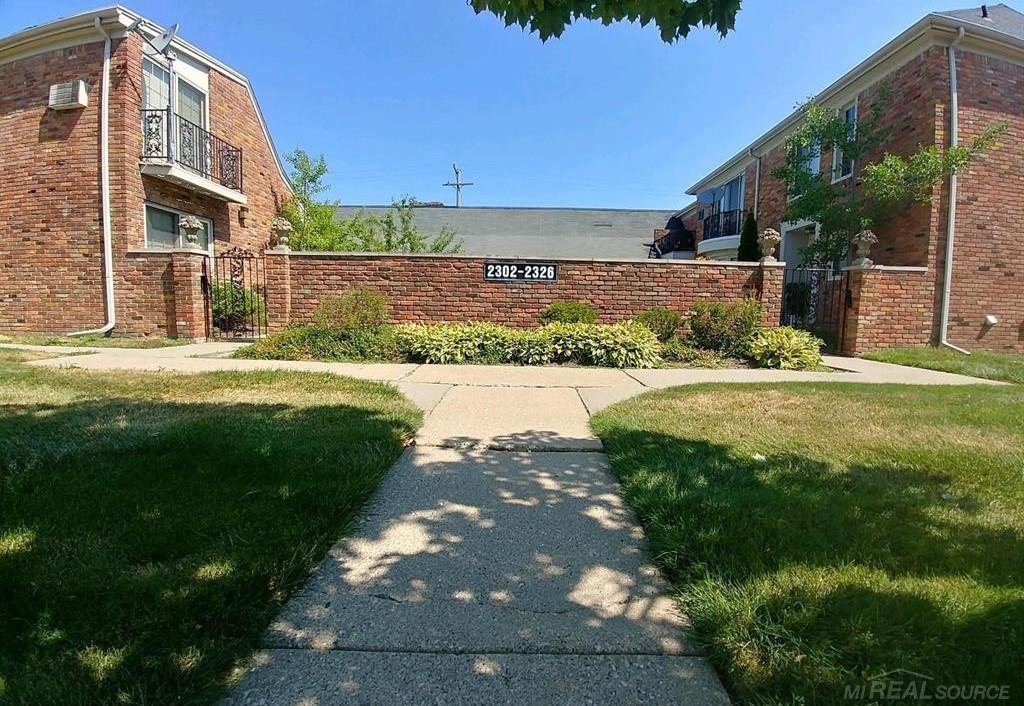 Brick multifamily buildings flank a landscaped walkway leading to an entrance marked 2302-2326.