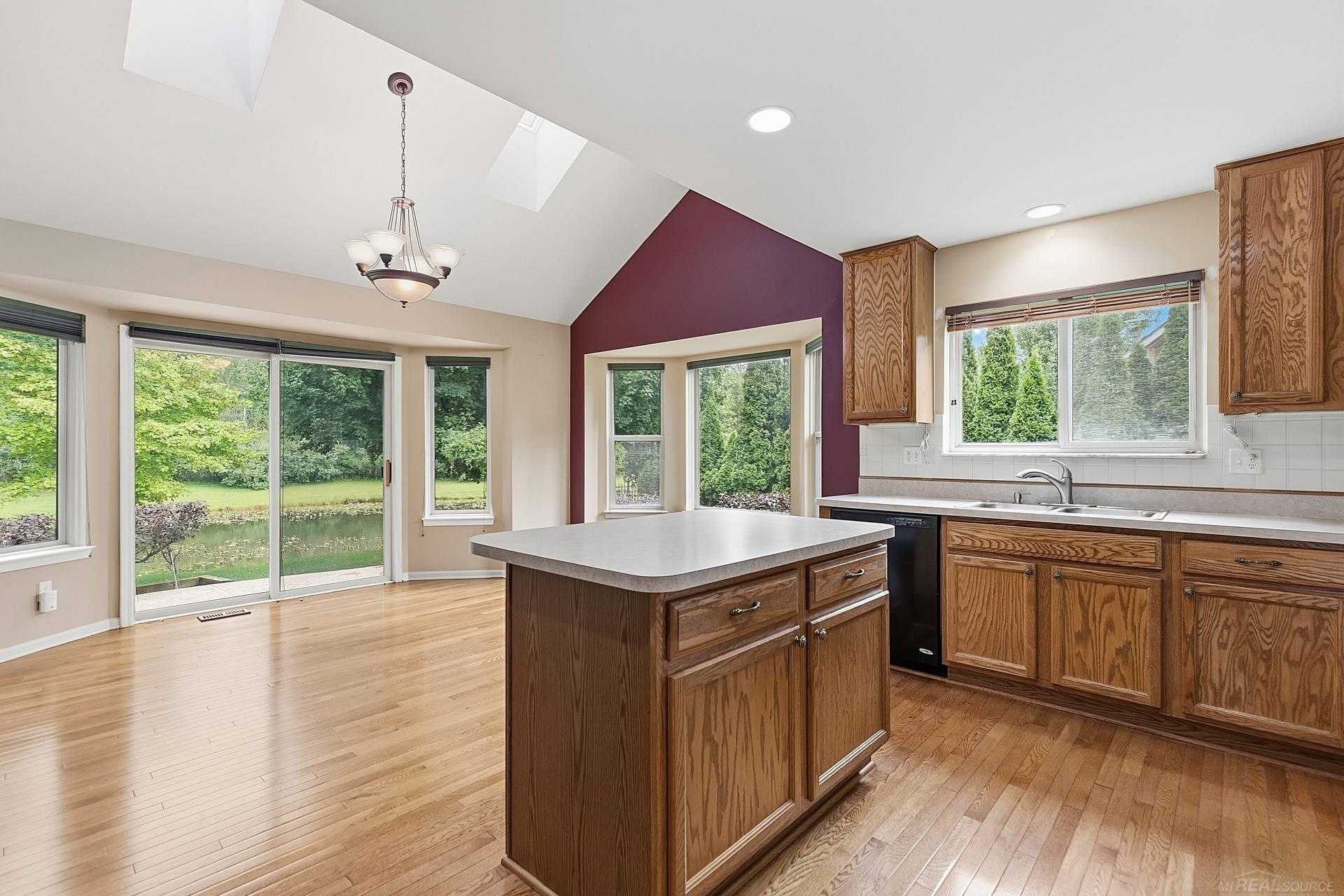 Kitchen with oak cabinets, a large island, hardwood floors, and windows overlooking a pond.