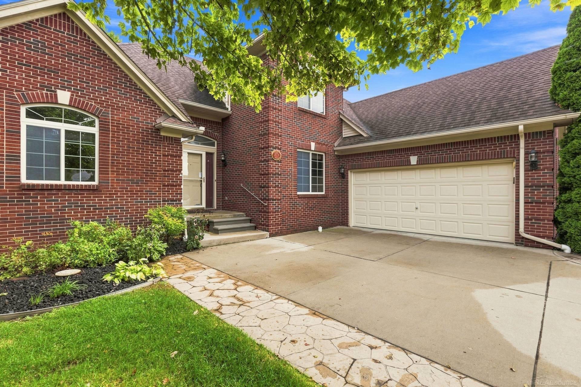Red brick house with an arched window, landscaped entry, and attached two-car garage.