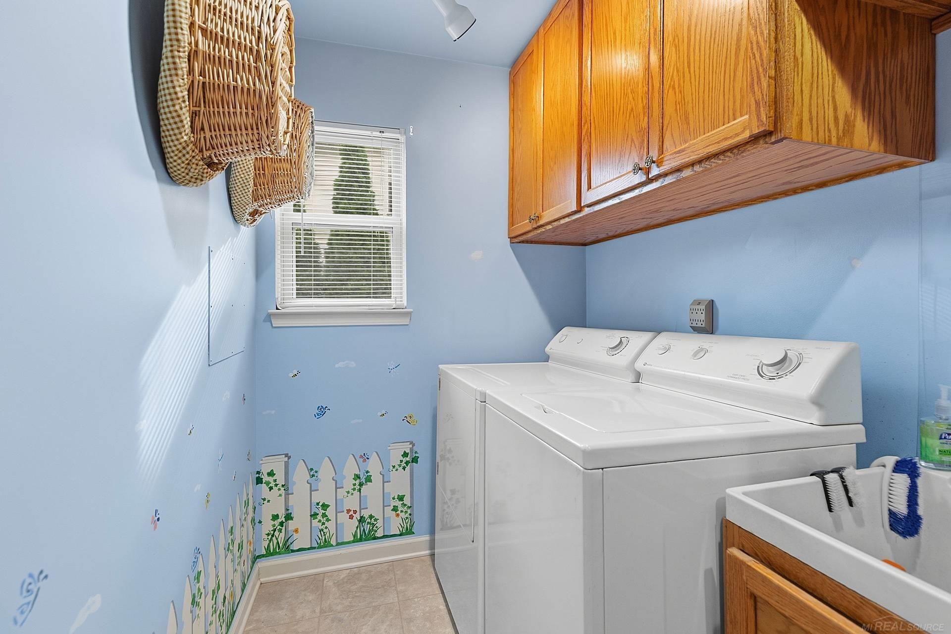 Laundry room with a white washer and dryer, oak cabinets, and a utility sink.