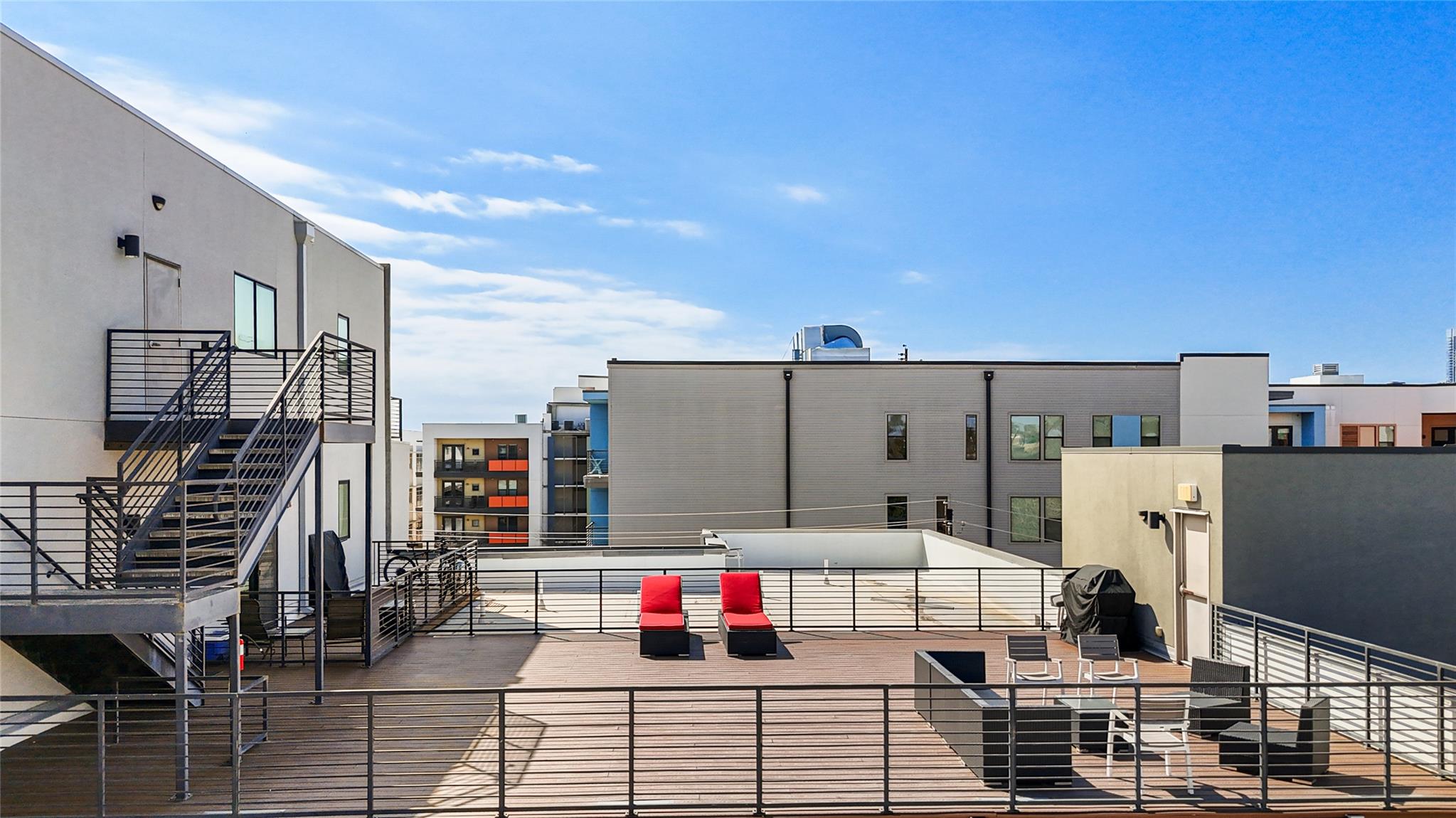 Rooftop deck with red lounge chairs, patio seating, and an outdoor grill