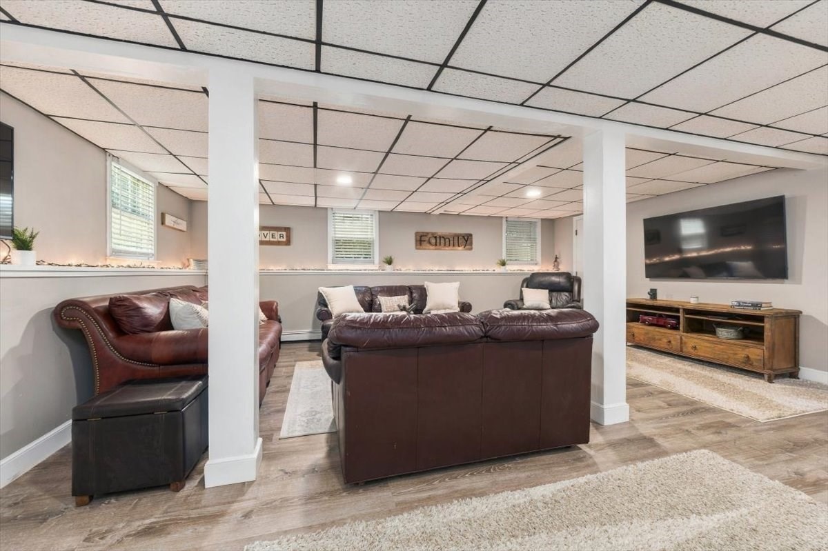 Furnished family room with leather sofas, wall-mounted television, and tiled drop ceiling.