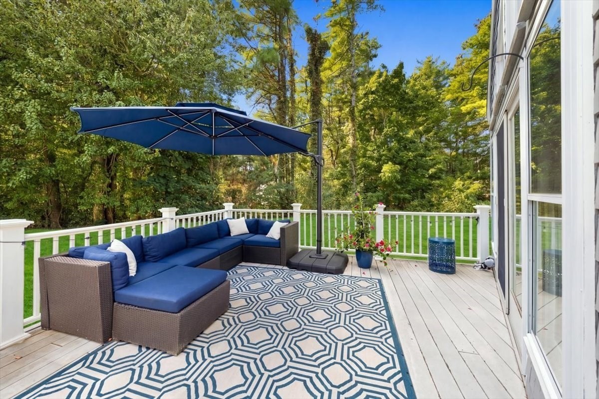Outdoor deck with blue sectional and umbrella overlooking a wooded yard