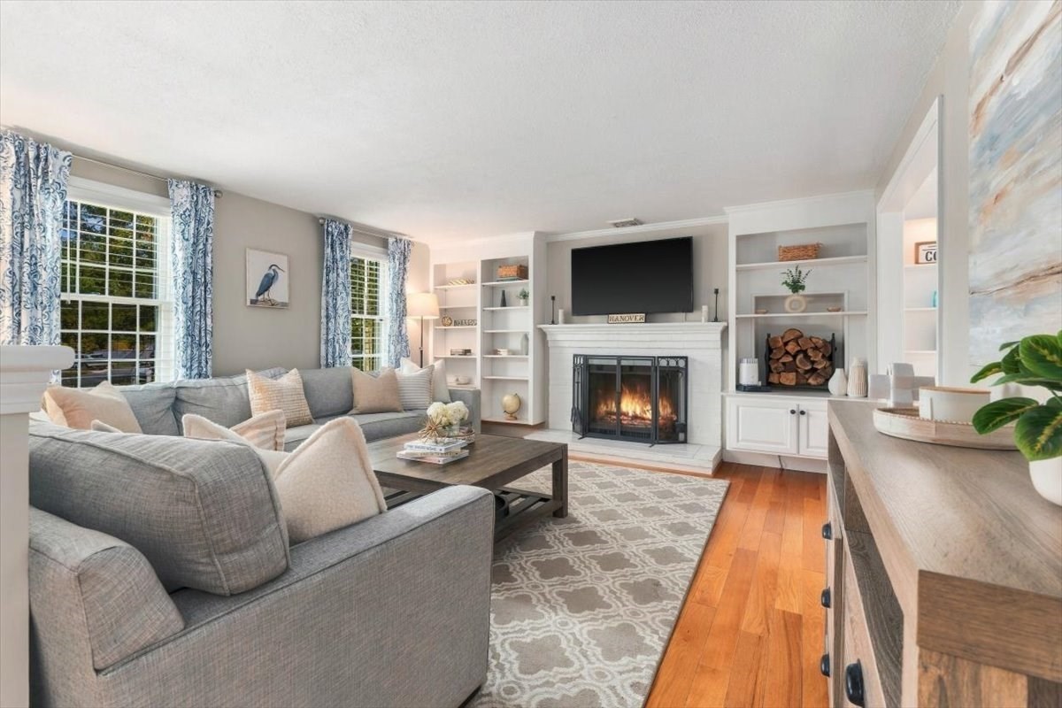 Living room with a gray sectional, built-in shelves, and a lit fireplace.