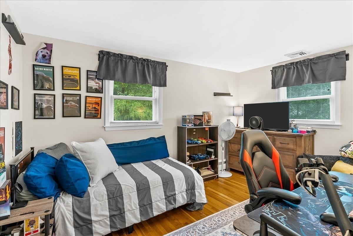 Bedroom with blue and gray daybed, hardwood floors, car posters, and a gaming setup.