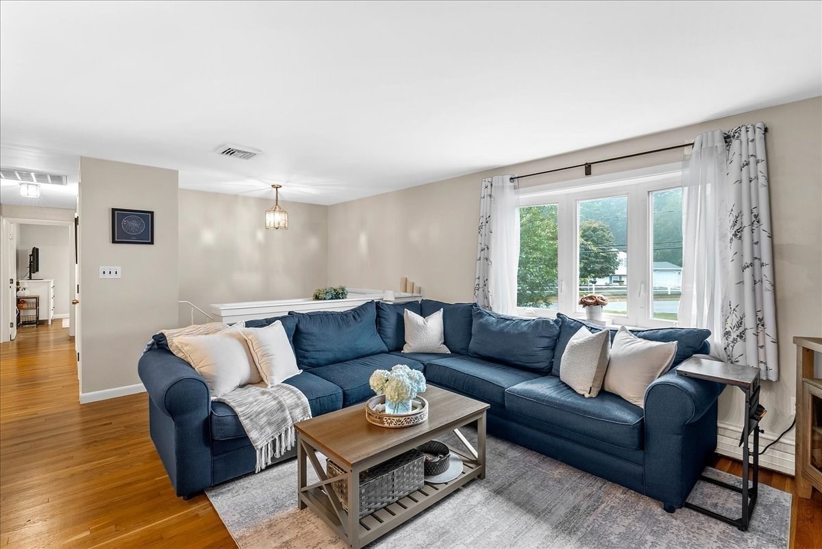 Living room with a navy sectional, patterned rug, and large curtained windows.