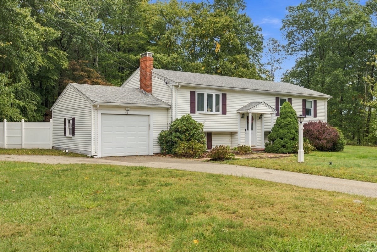 White split-level house with an attached garage, burgundy shutters, and a broad front lawn.