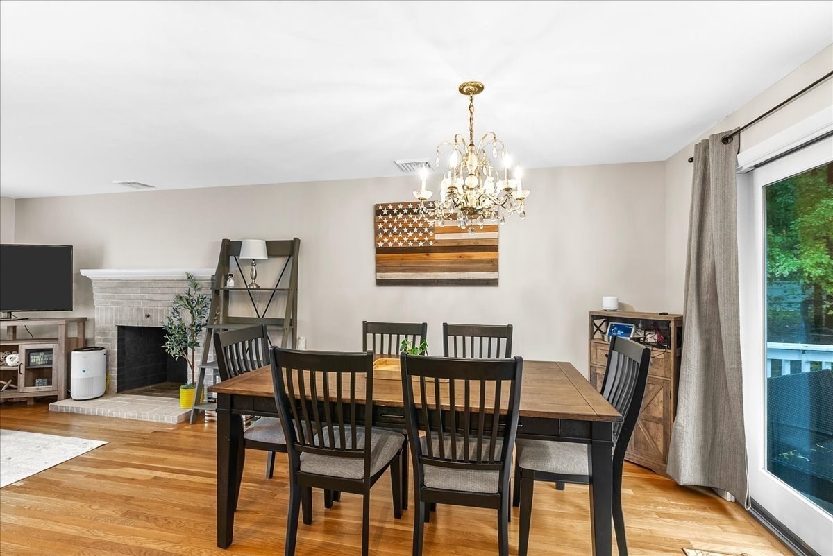 Dining room with a wood table, chandelier, brick fireplace, and sliding glass door.