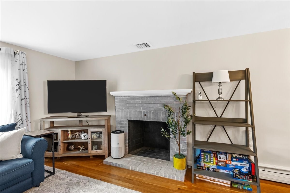 Living room with a gray brick fireplace, television, wooden shelving, and blue sofa.