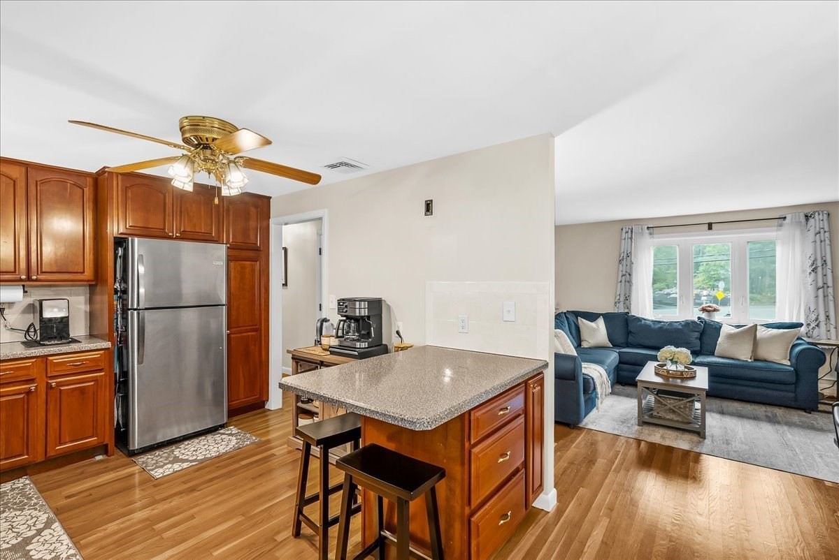 Kitchen with wood cabinetry and granite island opening onto a living room with a blue sectional.