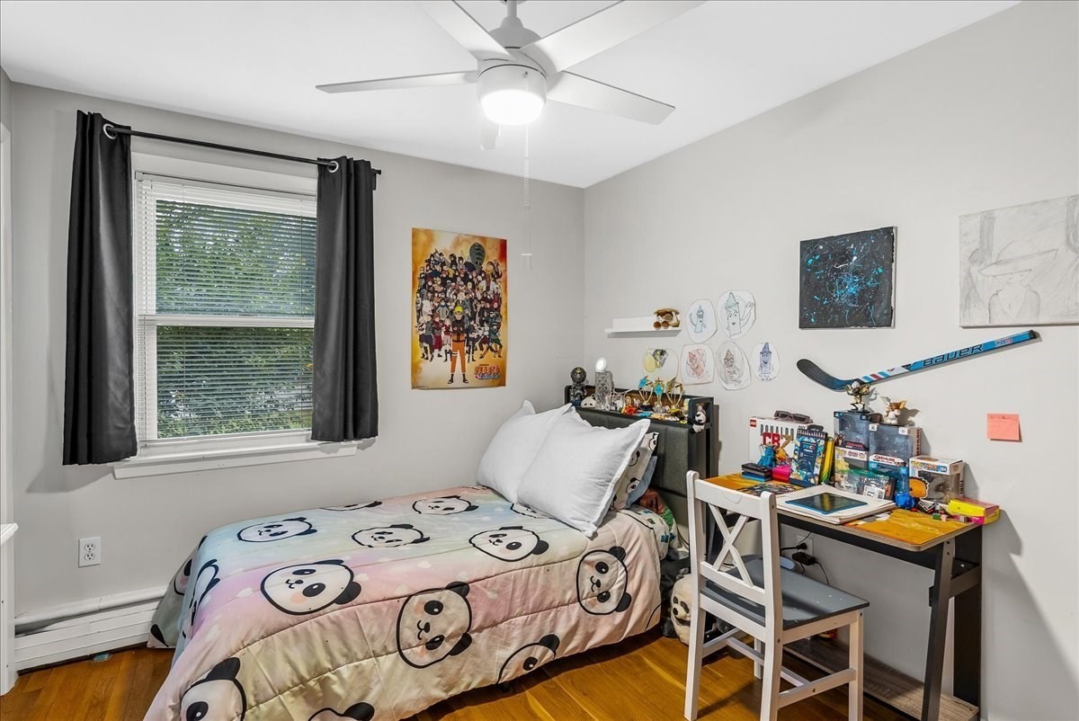 Bedroom with panda-print bedding, a collectibles-covered desk, hockey memorabilia, and hardwood floors.
