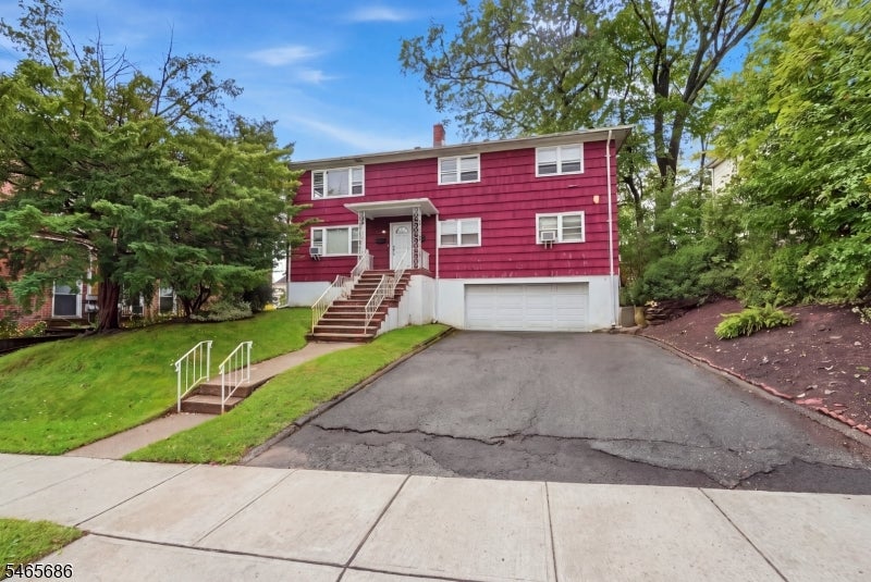 Red two-story house with a garage, front steps, and a wide driveway.