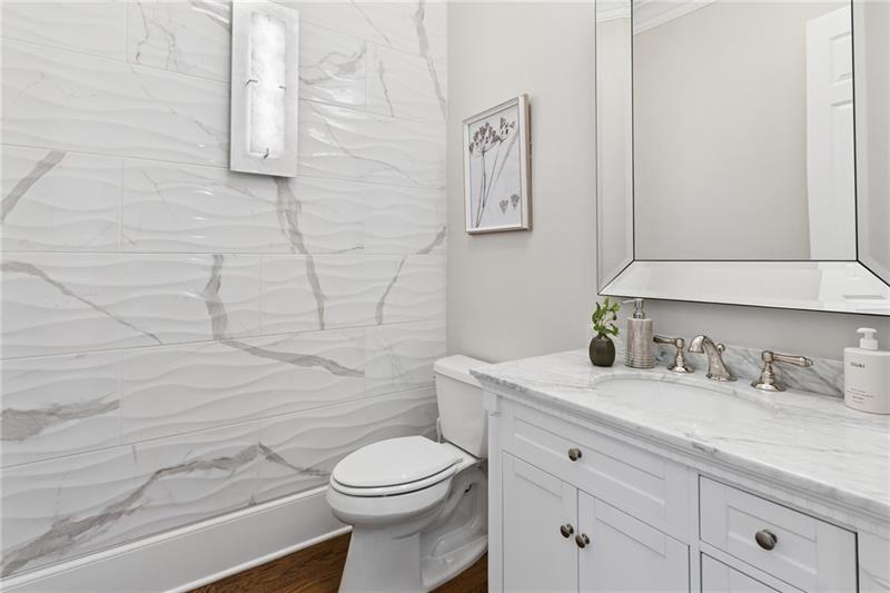 Renovated bathroom with wavy marble-look shower tile and a white marble vanity countertop.