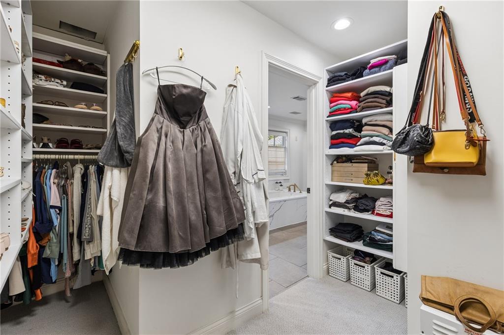 Walk-in closet with organized clothing shelves, hanging garments, and a bathroom doorway.