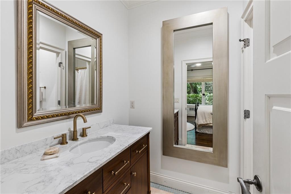 Bathroom vanity with a marble-pattern counter and ornate mirror, opening onto a bedroom.
