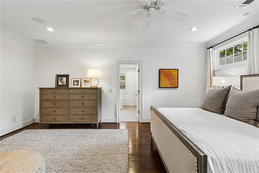 Bedroom with a large bed, hardwood floors, and a tall curtained window.