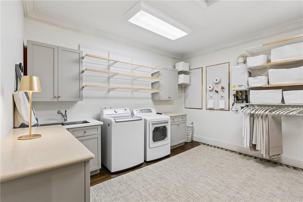 Laundry room with washer and dryer, utility sink, gray cabinets, and extensive shelving and hanging storage.