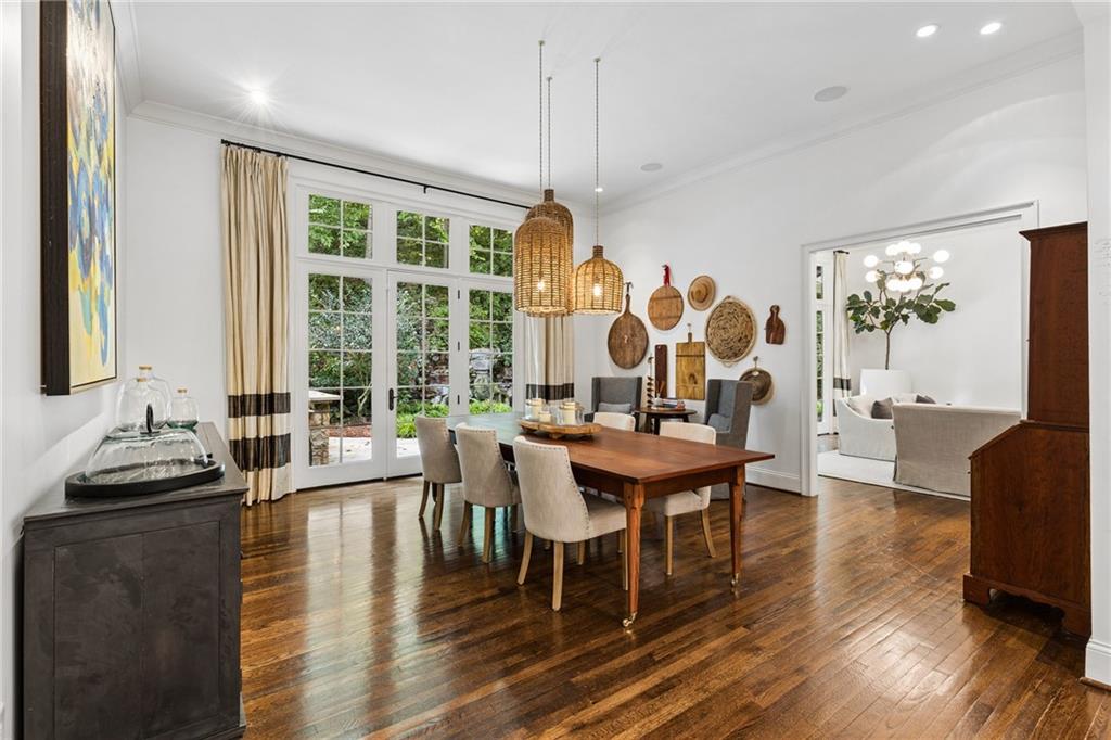 Dining room with a wooden table, woven pendant lights, hardwood floors, and French doors opening to greenery.
