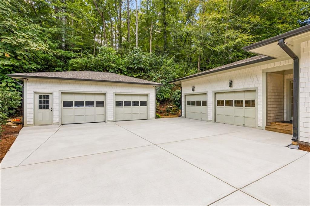 White-brick detached and attached garages with multiple doors and a broad concrete driveway.