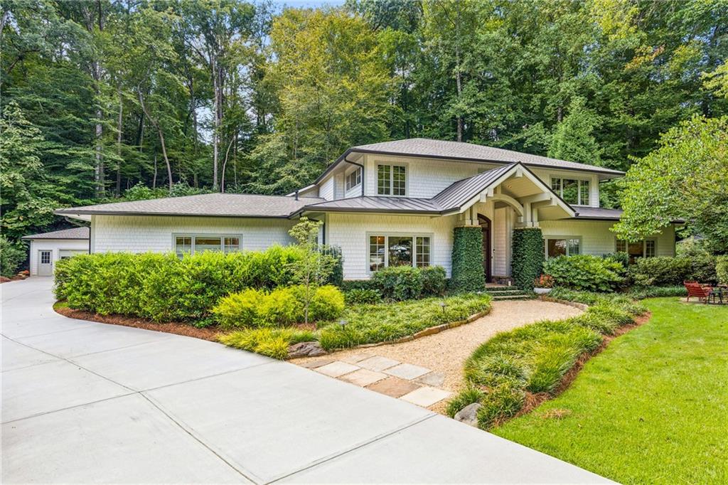 White two-story home with a covered arched entry, landscaped garden, and broad concrete driveway.