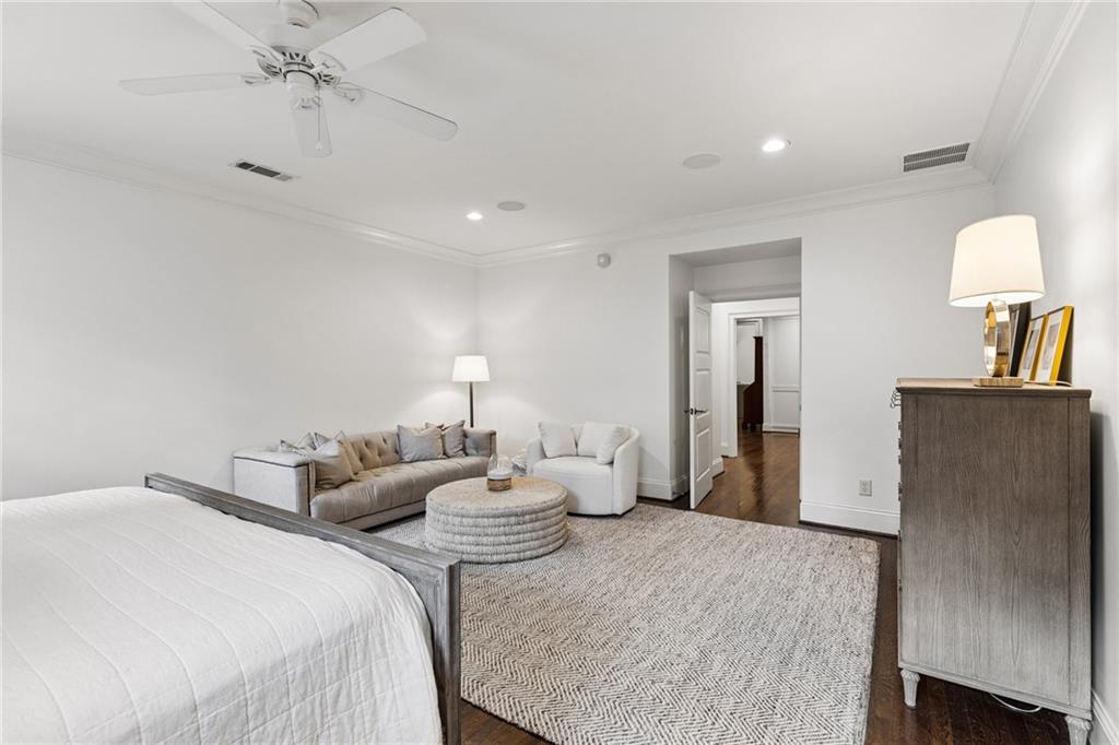 Furnished bedroom with a large bed, sitting area, ceiling fan, and patterned rug.