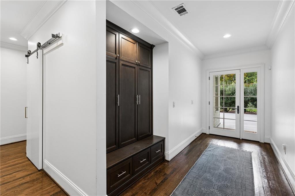 Entry hall with built-in dark wood storage and bench, patterned runner, and glass-paneled French doors.