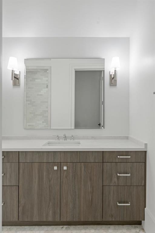 Bathroom vanity with dark wood cabinetry, white countertop, wide mirror, and wall sconces.