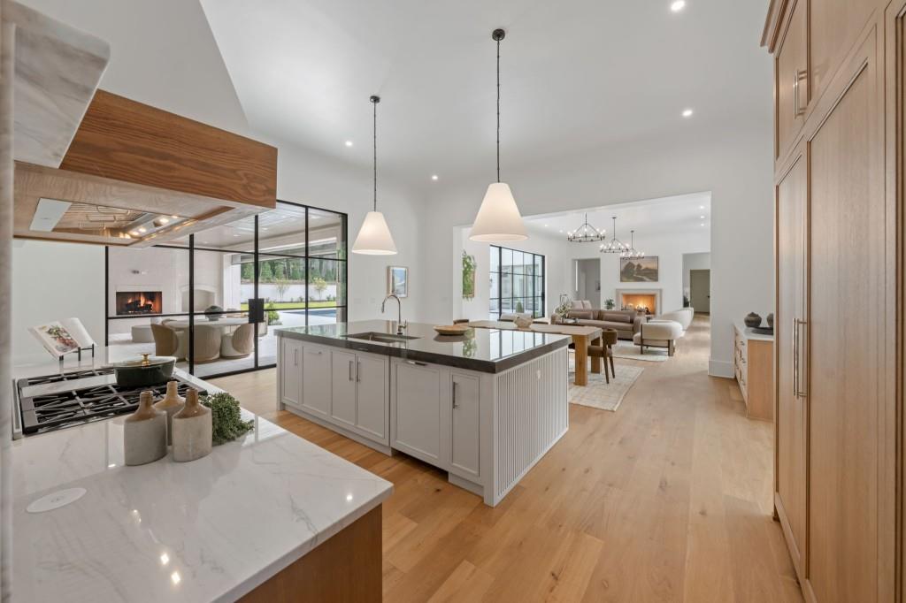 Modern kitchen with a large island, wood cabinetry, and glass doors overlooking a pool.