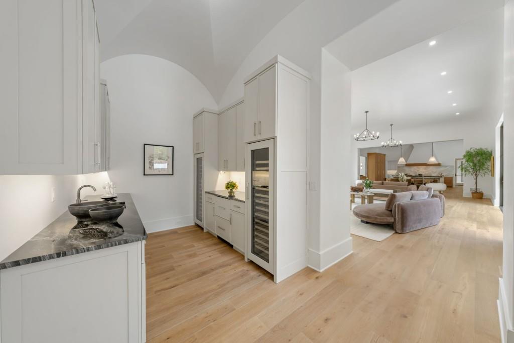 Kitchen with white cabinetry and a dark stone counter opens to a vaulted living and dining area.