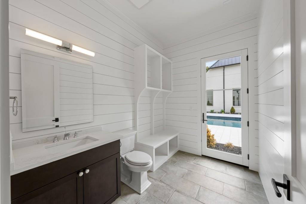 Bright bathroom with a dark vanity, built-in bench, and glass door overlooking the pool.