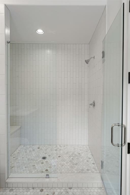 Walk-in shower with white vertical tile, mosaic floor, built-in bench, and clear glass door.
