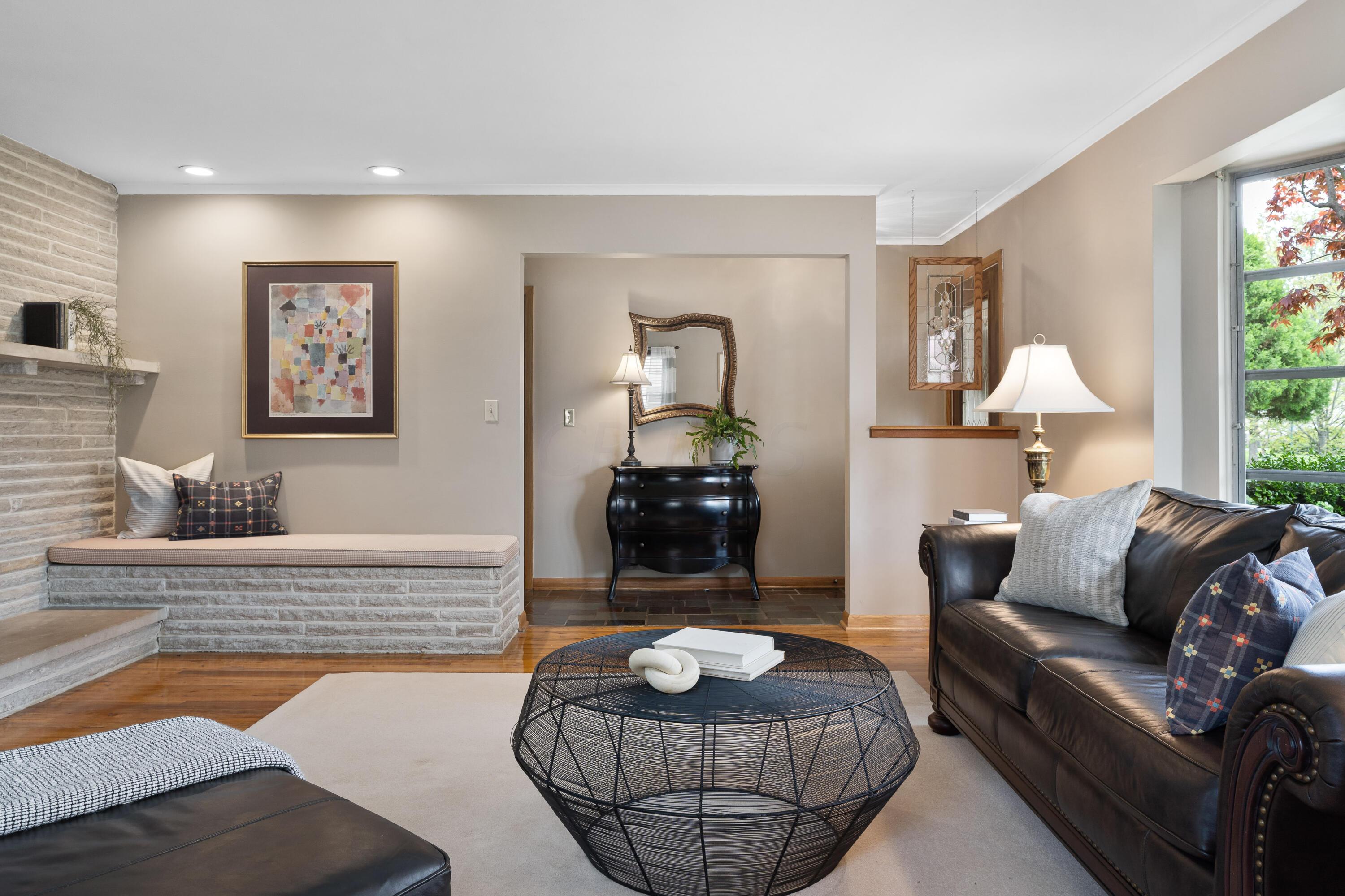 Living room with a stone fireplace, built-in bench, leather sofas, and a round wire coffee table.