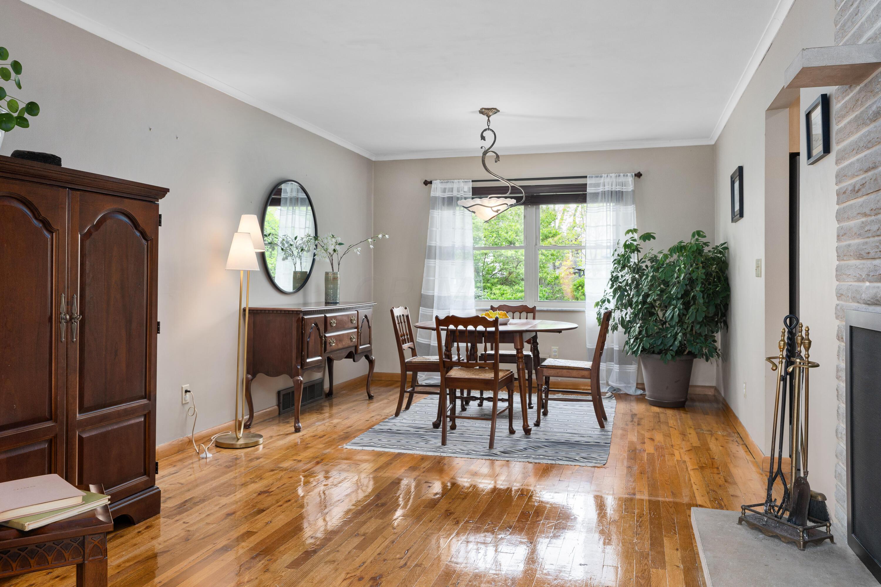 Furnished dining room with a wooden dining set, polished hardwood floors, and a stone fireplace.
