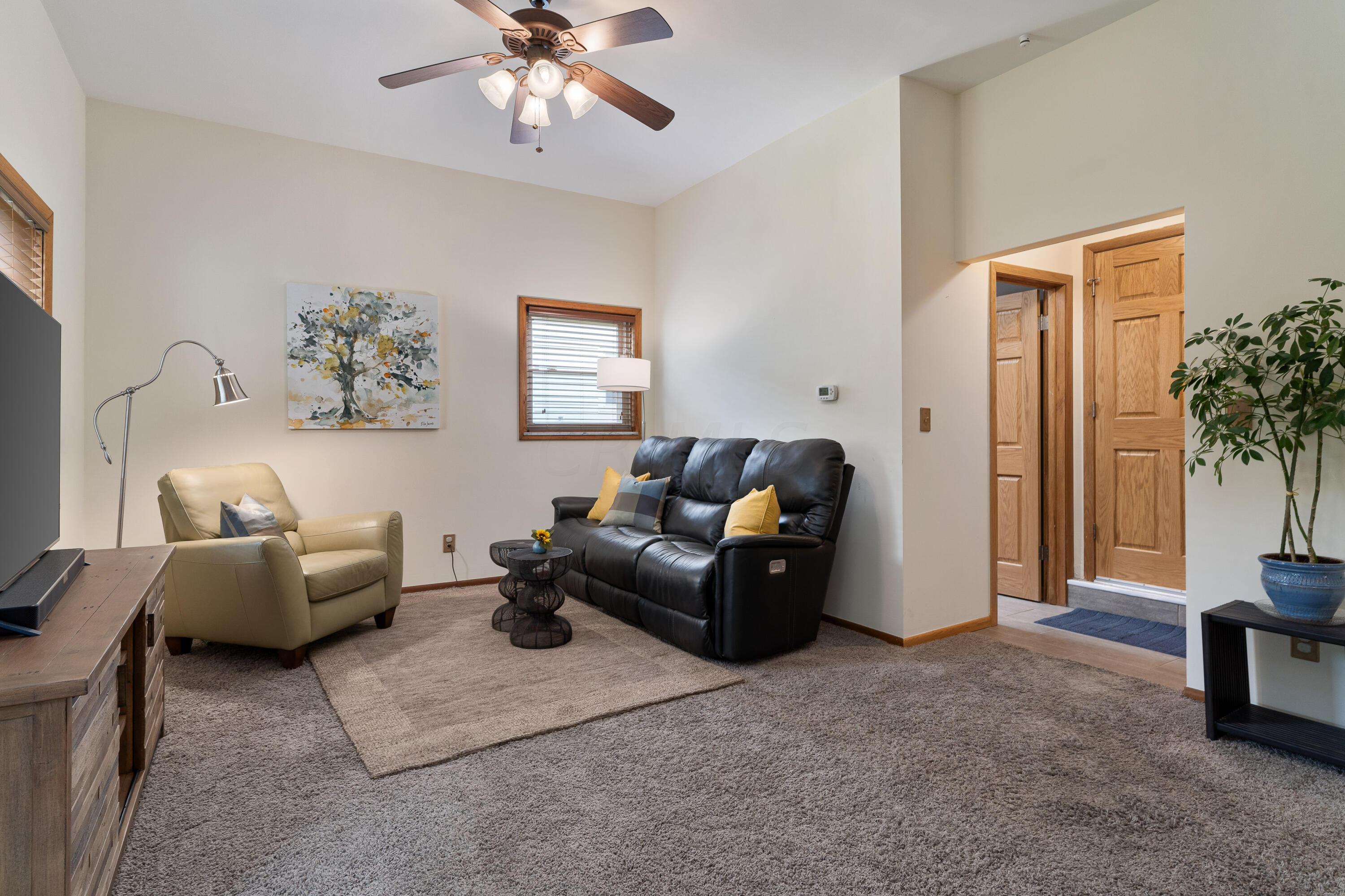 Living room with a black leather sofa, cream recliner, and wood-trimmed doorway.