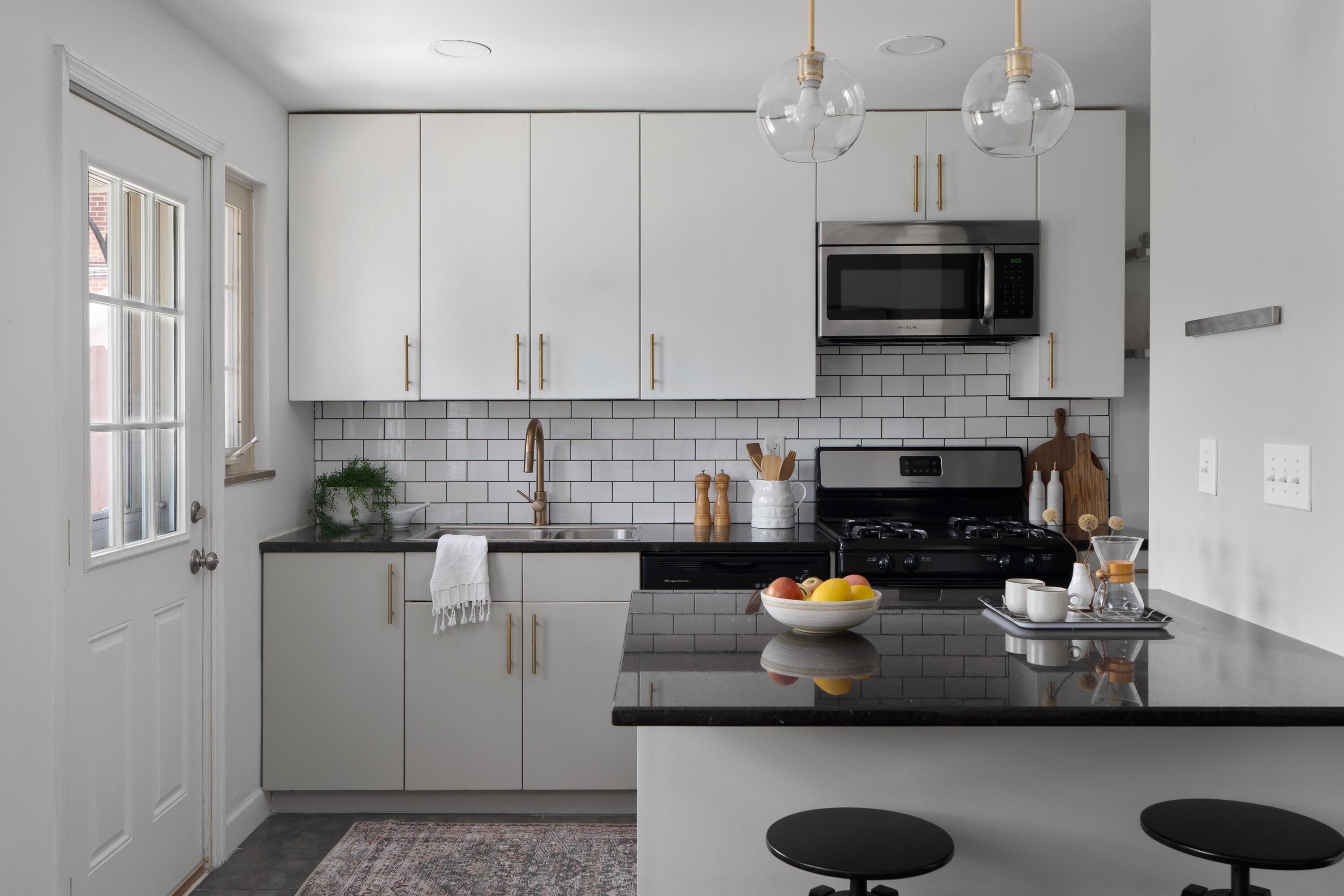Modern kitchen with white cabinets, subway tile backsplash, black countertops, and a large island.