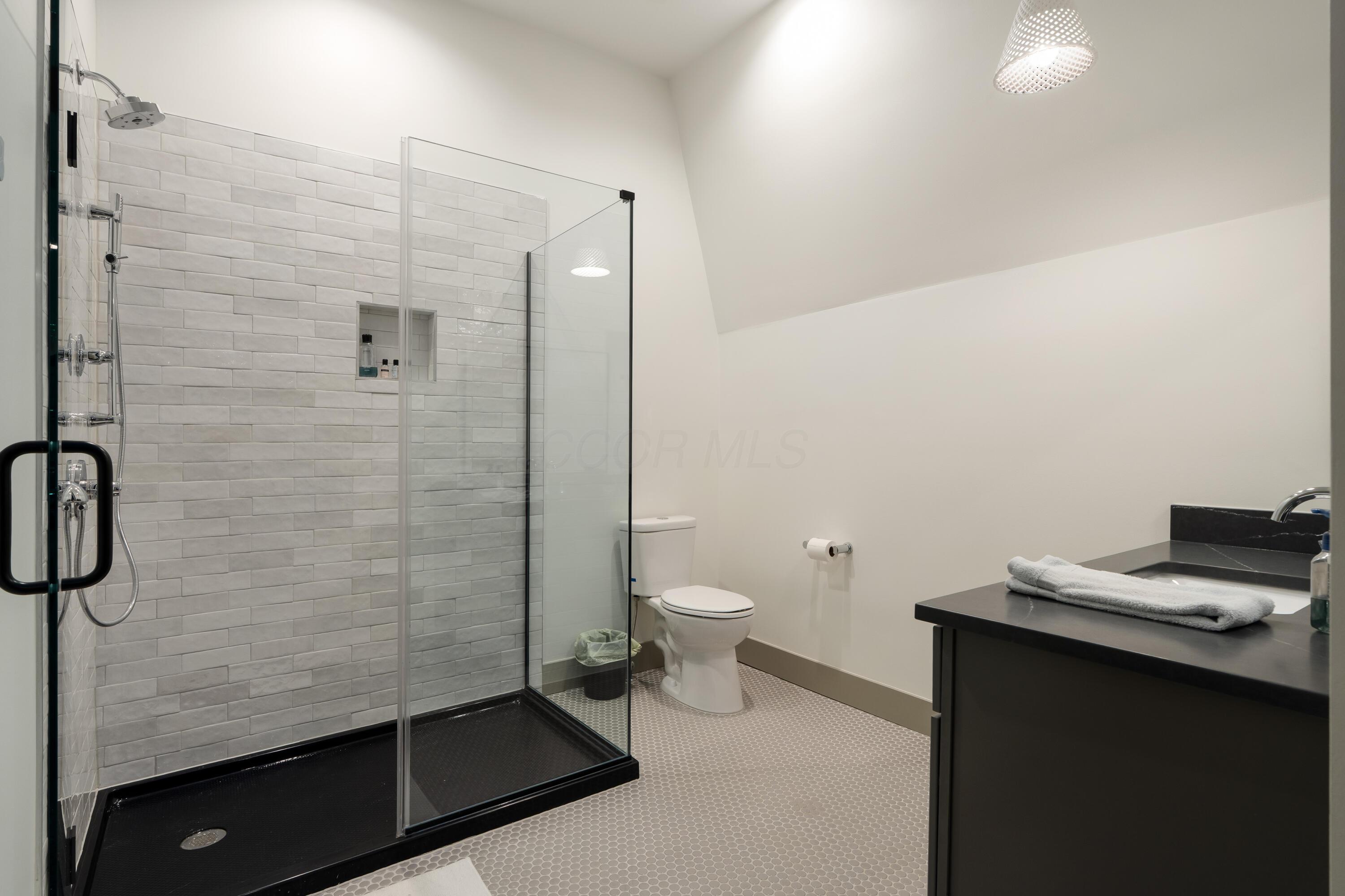 Bathroom with a glass-enclosed gray-tile walk-in shower and black vanity.