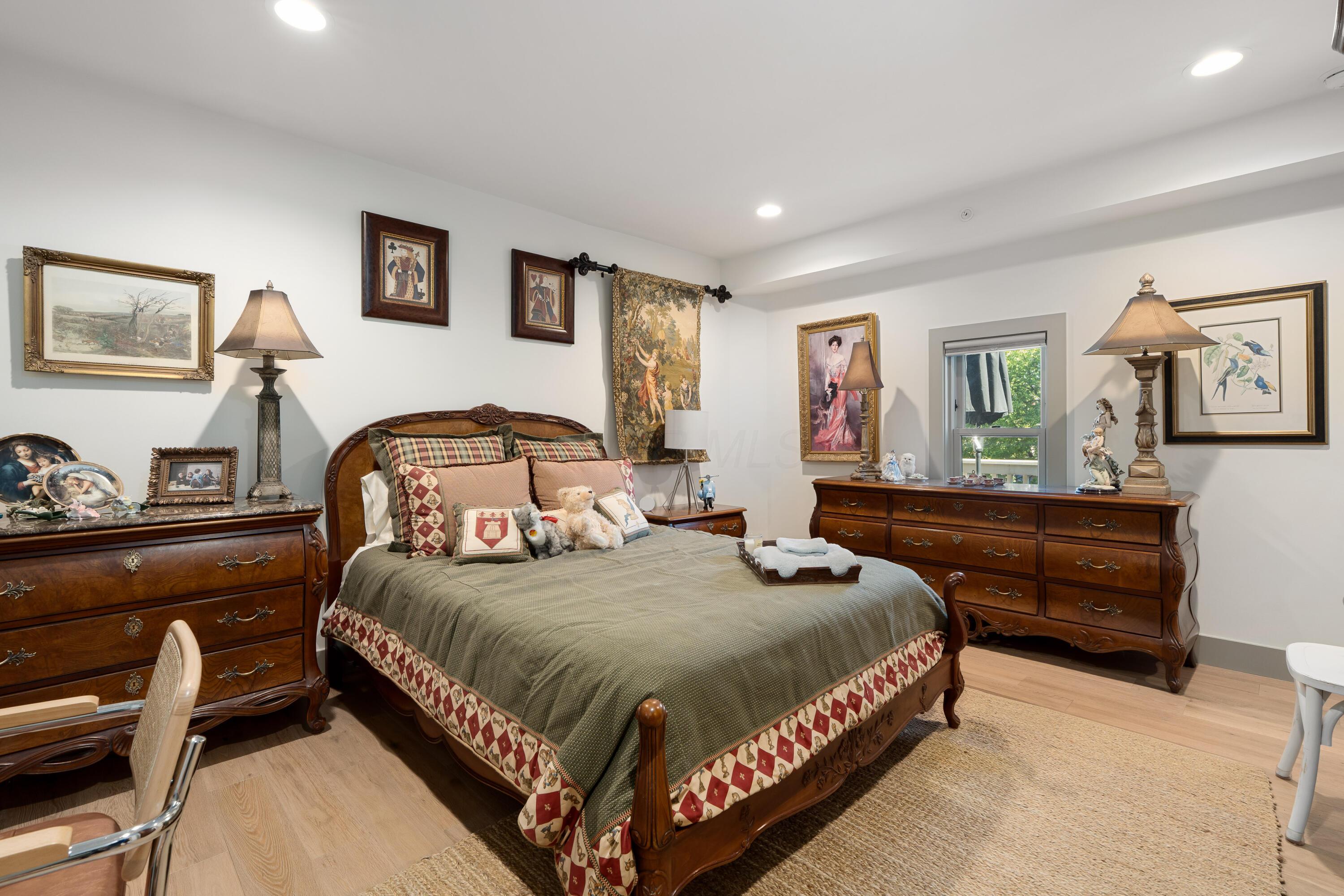 Furnished bedroom with an ornate wooden bed, patterned bedding, and matching antique dressers.
