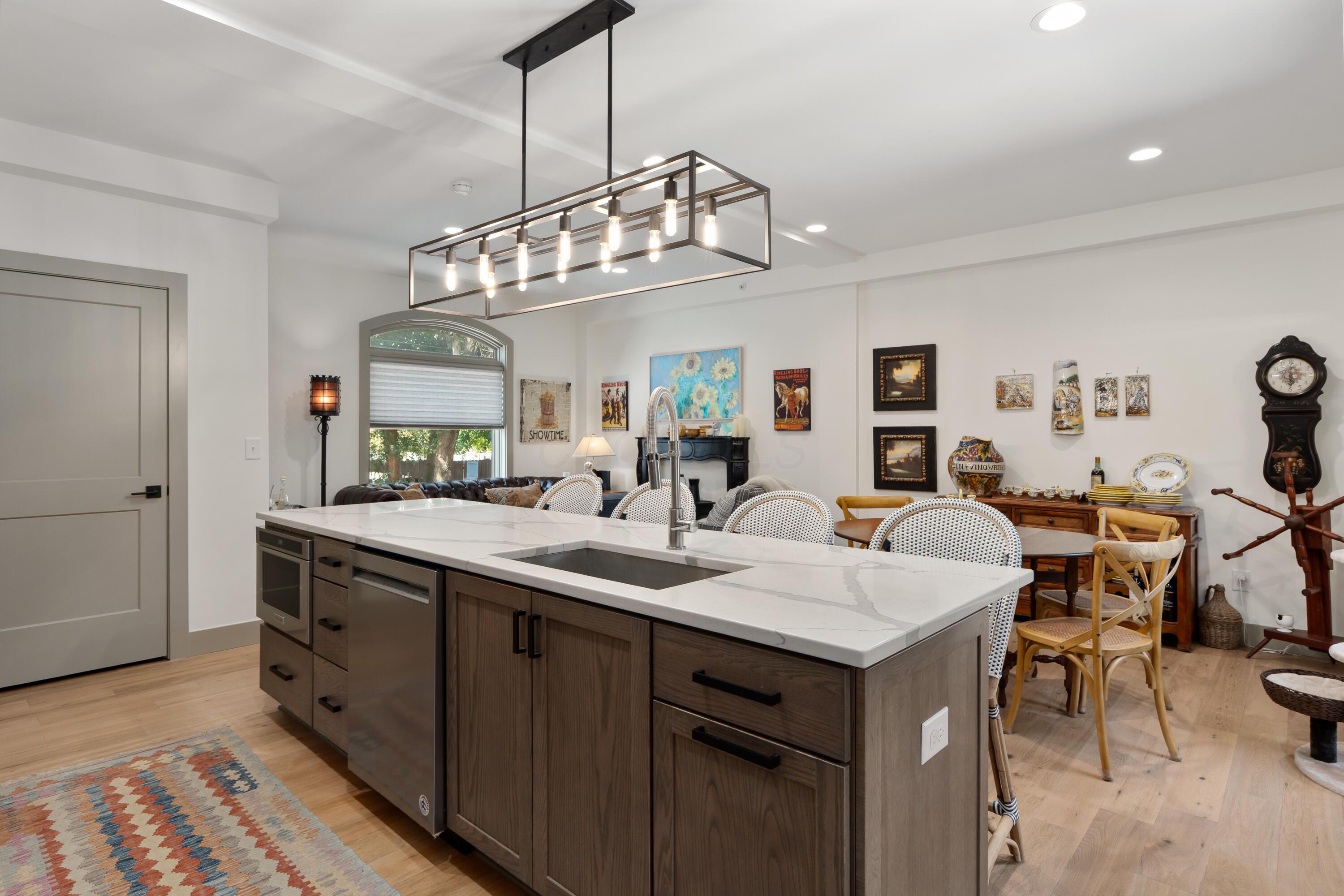 Kitchen with a large white countertop island, dark wood cabinets, and a rectangular pendant light.