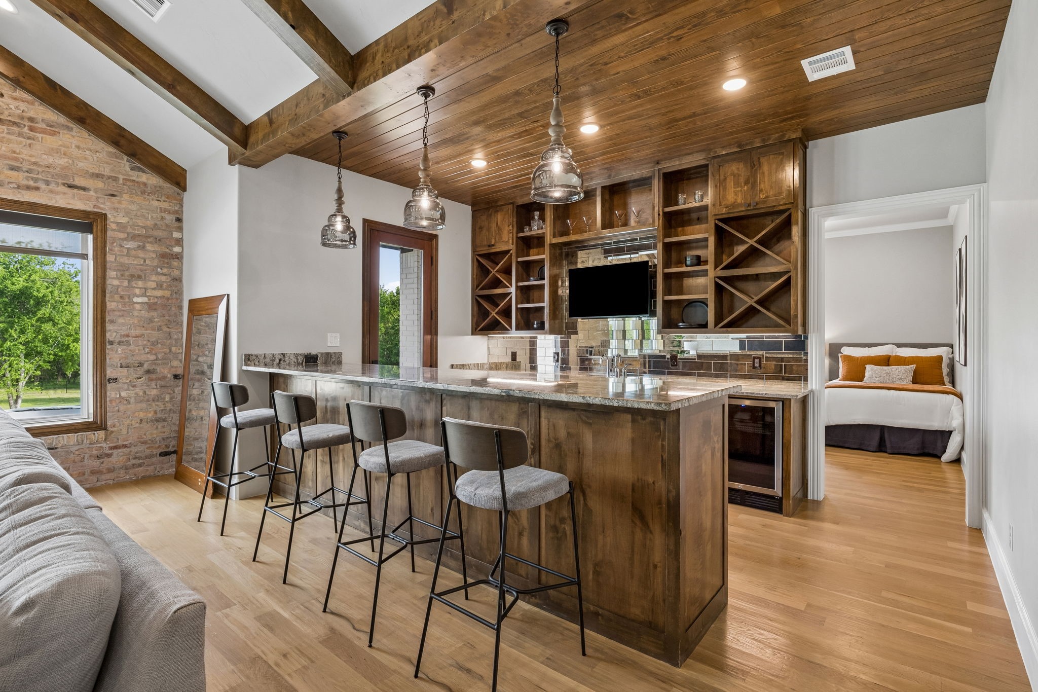 Kitchen bar with a large wood island, four stools, custom cabinetry, and exposed brick wall.