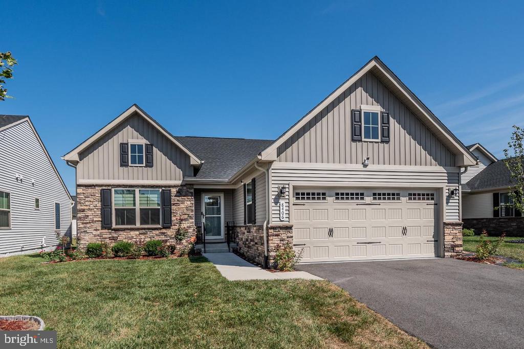 Gray-sided home with stone accents, a two-car garage, and a front lawn.