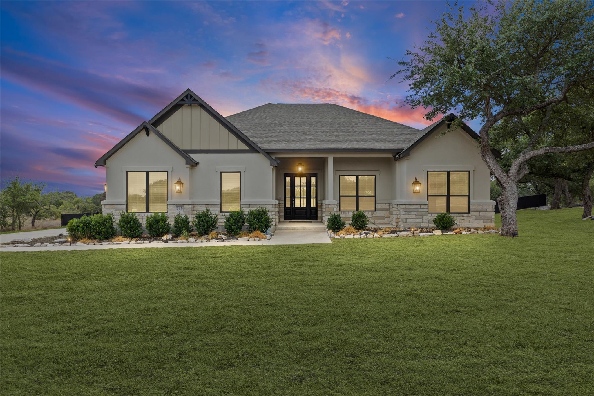 Single-story home with stone accents and a broad lawn beneath a colorful dusk sky.