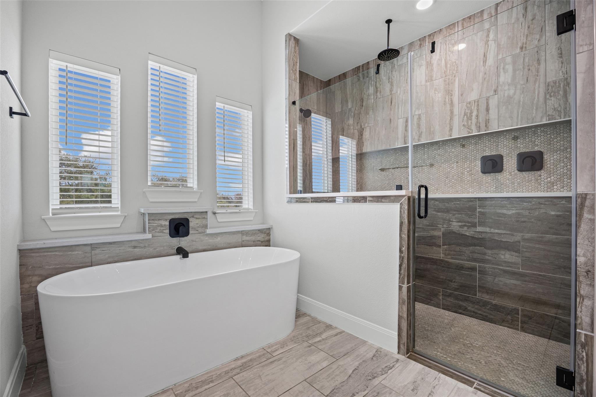 Primary bathroom with a freestanding soaking tub and a glass-enclosed tiled shower.