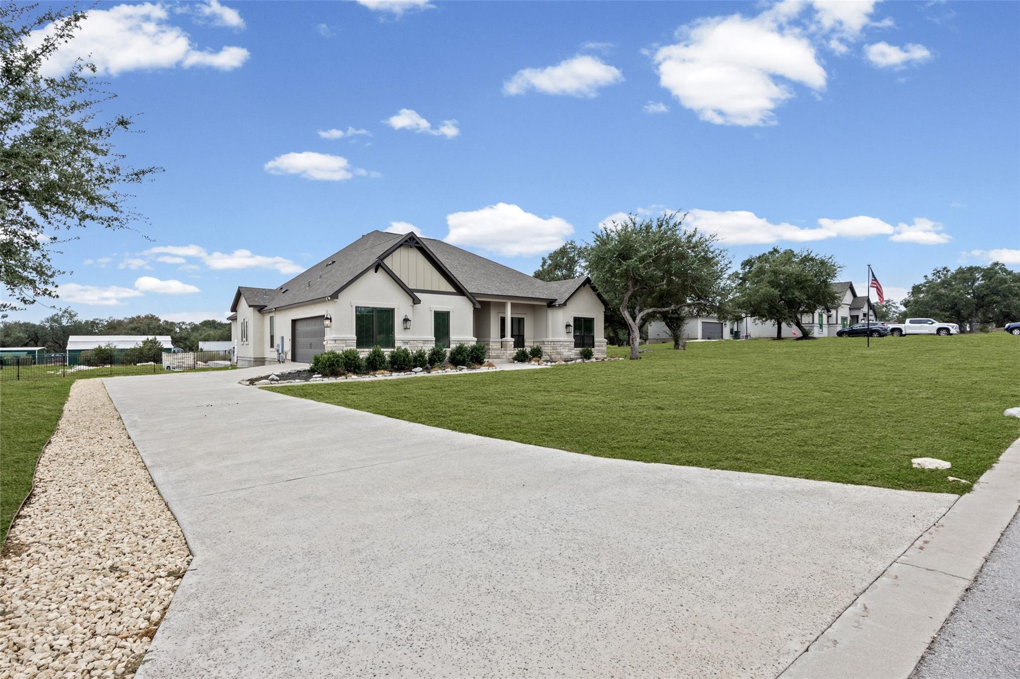 Single-story home with stone accents, a broad concrete driveway, and a manicured lawn.