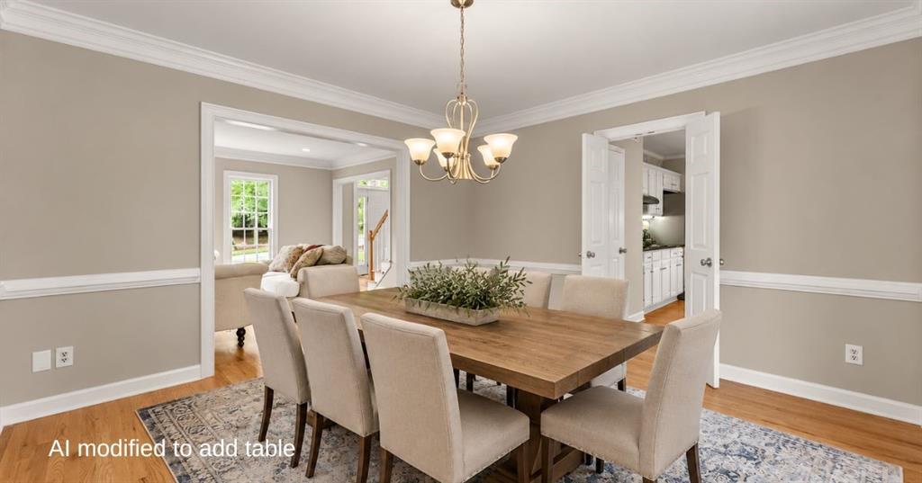 Dining room with a wooden table, upholstered chairs, chandelier, and patterned rug.