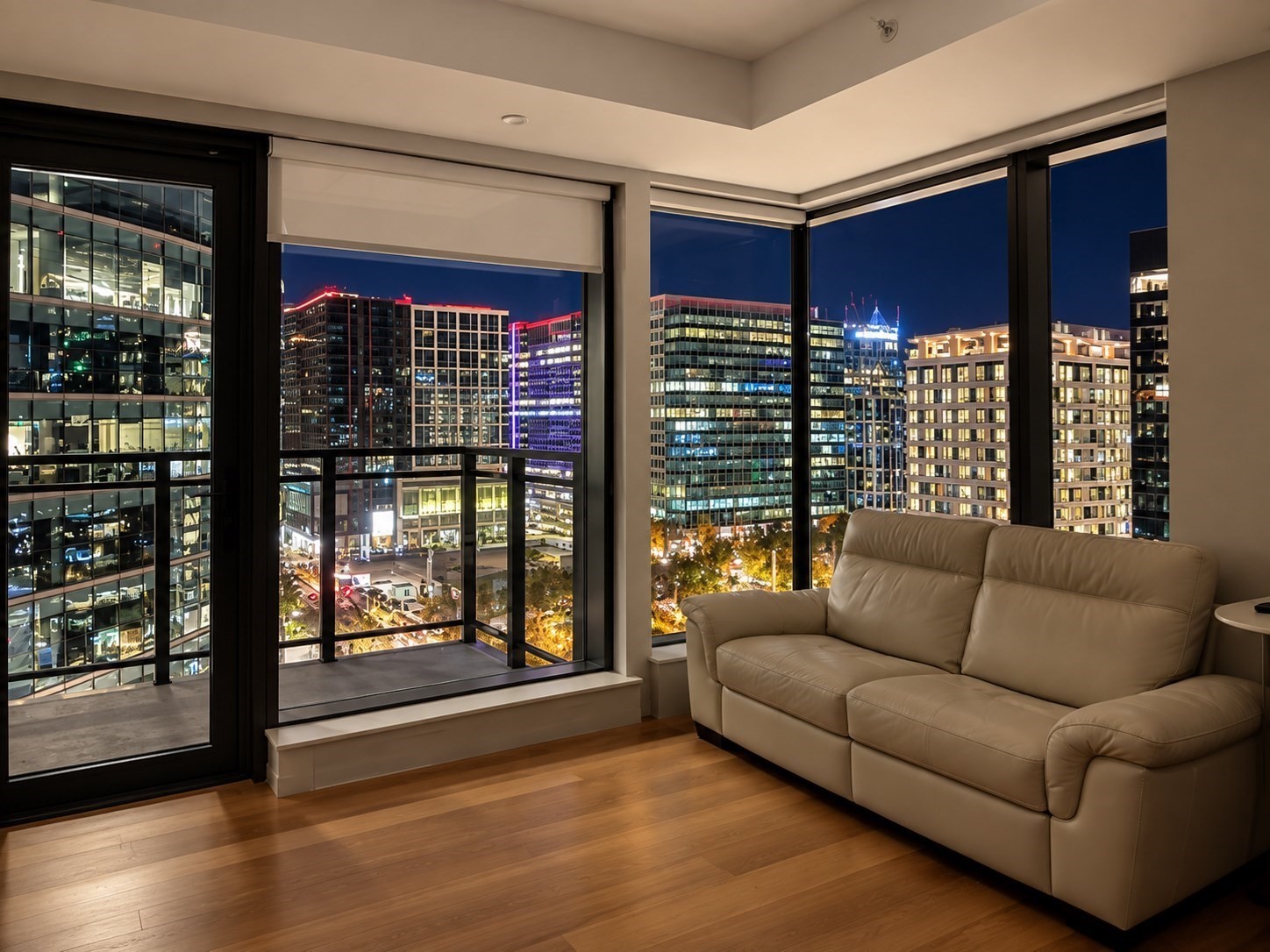 High-rise living room with a leather sofa and floor-to-ceiling windows overlooking the city at night.