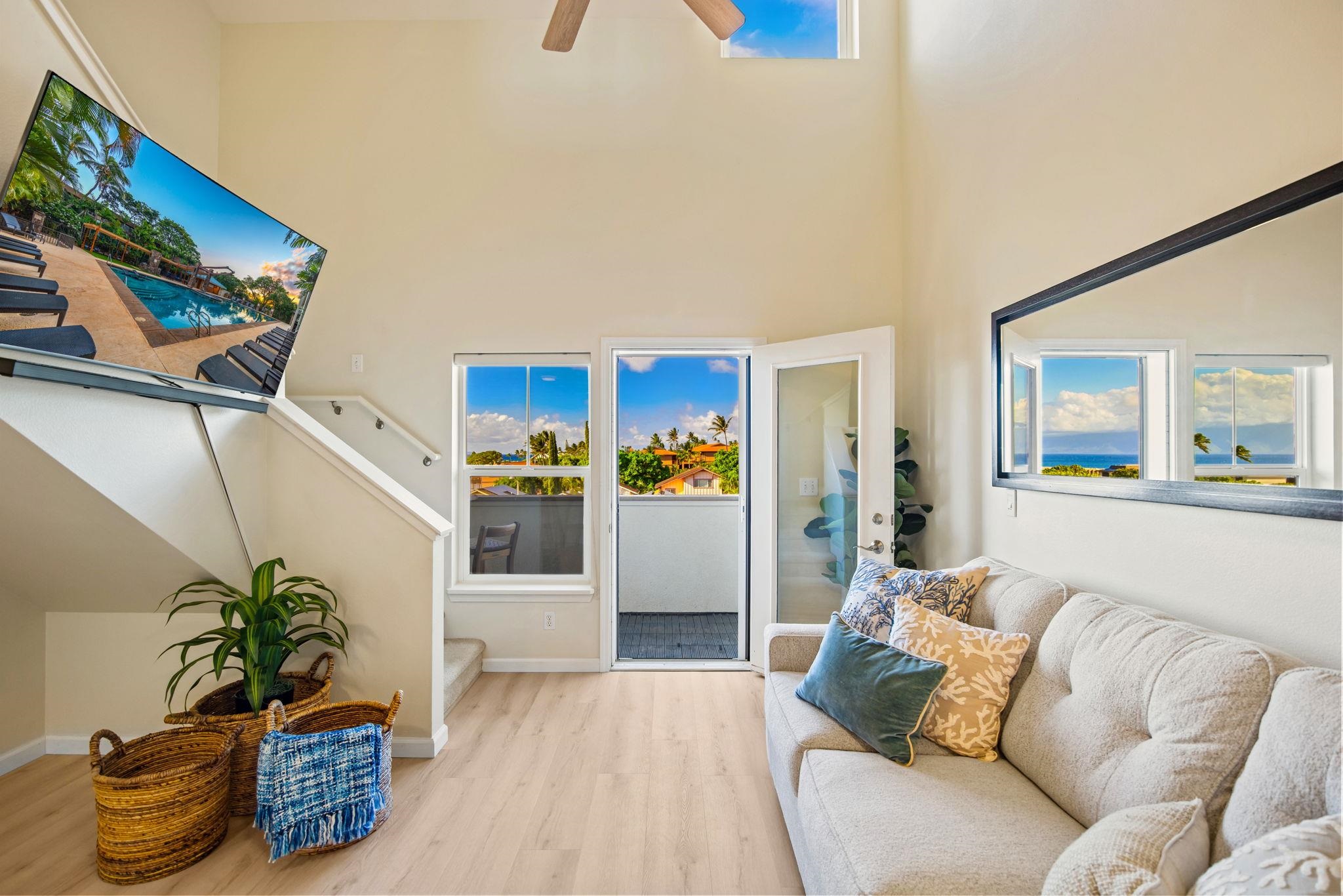 Staged living room with a vaulted ceiling, cream sofa, and ocean views through the windows.