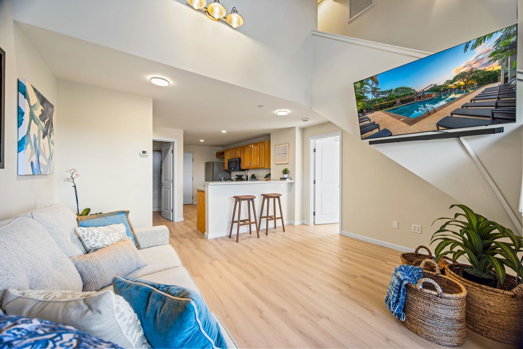 Open-plan living room and kitchen with a breakfast bar and a wall-mounted television.