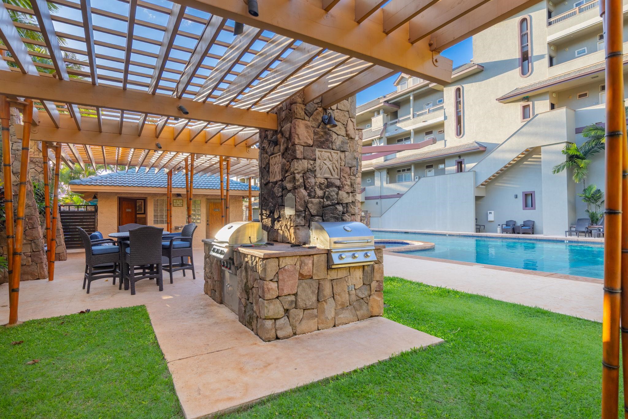 Condominium pool courtyard with a pergola-covered dining area and stone outdoor kitchen.