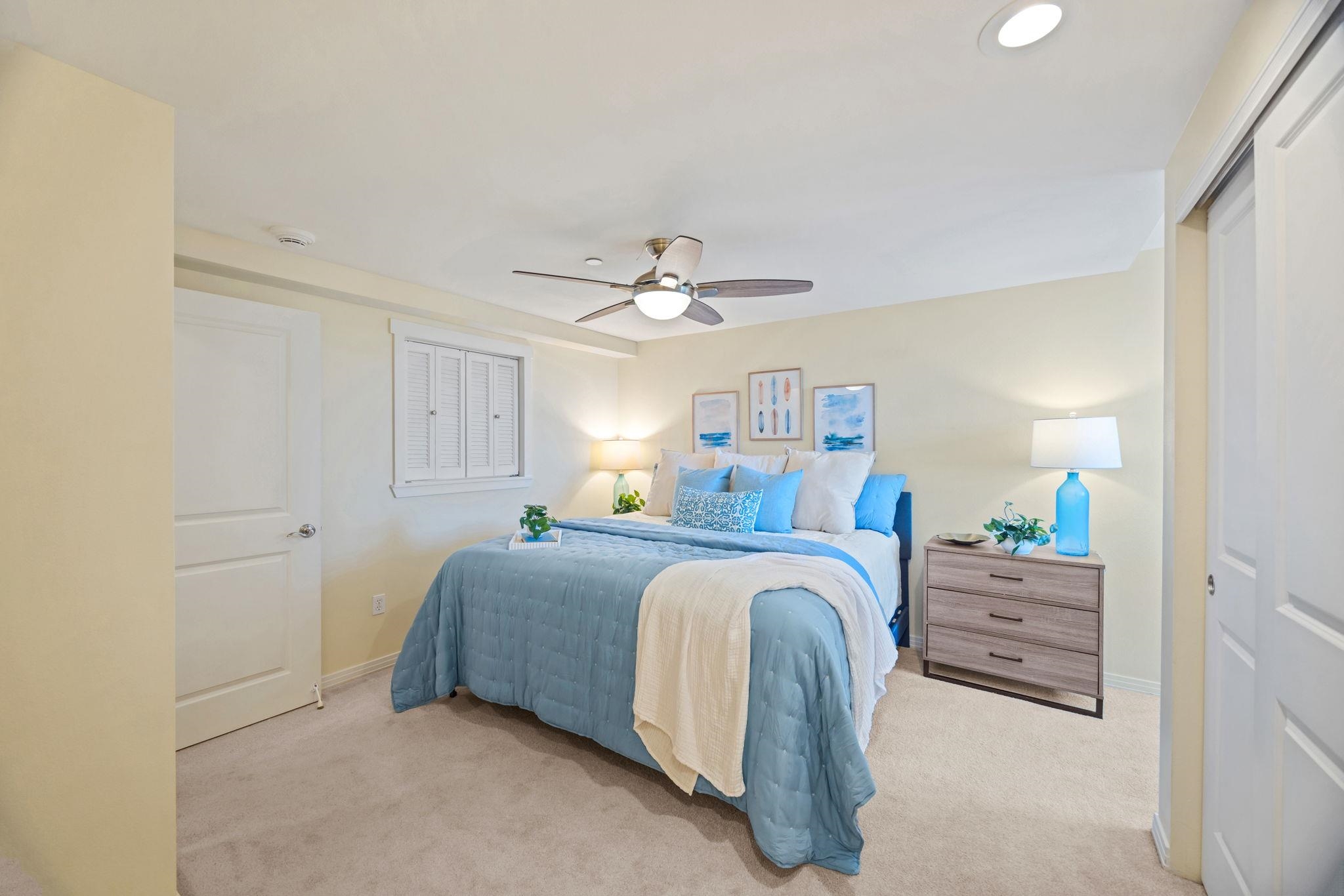 Furnished bedroom with a blue-and-white bed, ceiling fan, and wooden dresser.