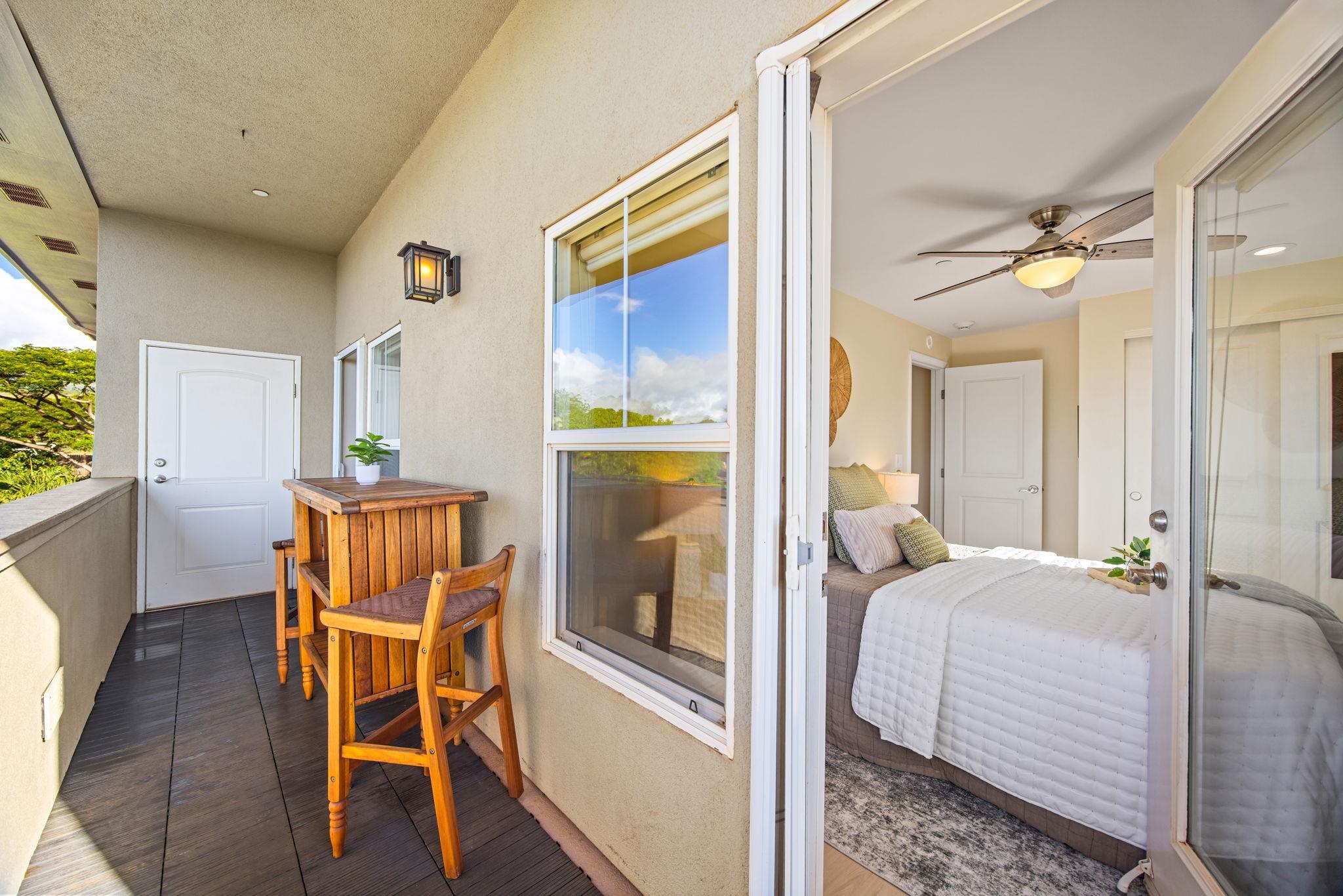 Furnished balcony with a wooden bistro set beside an open sliding door to a bedroom.